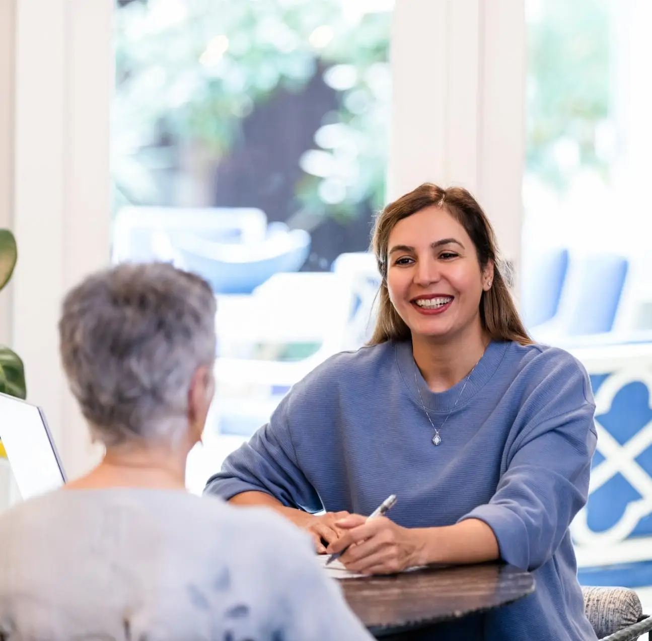 The mature adult financial advisor smiles while listening to her unrecognizable senior client.